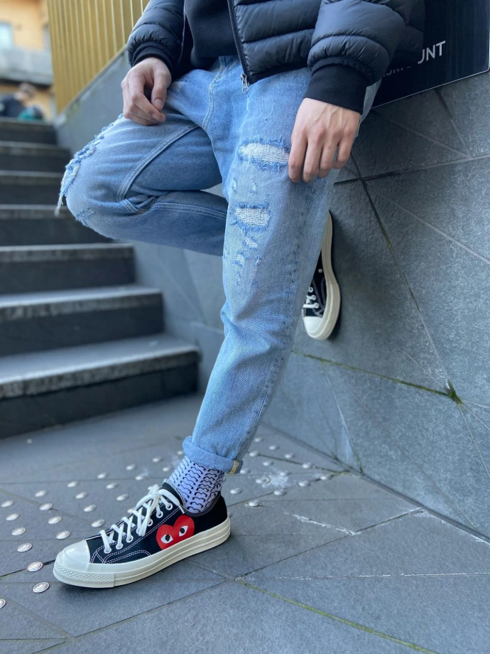 person in blue denim jeans and black and white converse all star high top sneakers